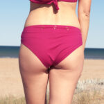 howBee SwimIt bikini briefs in beautyberry rose color with golden rings, which can be used to attach the ShowBee Fantasies. Back view.